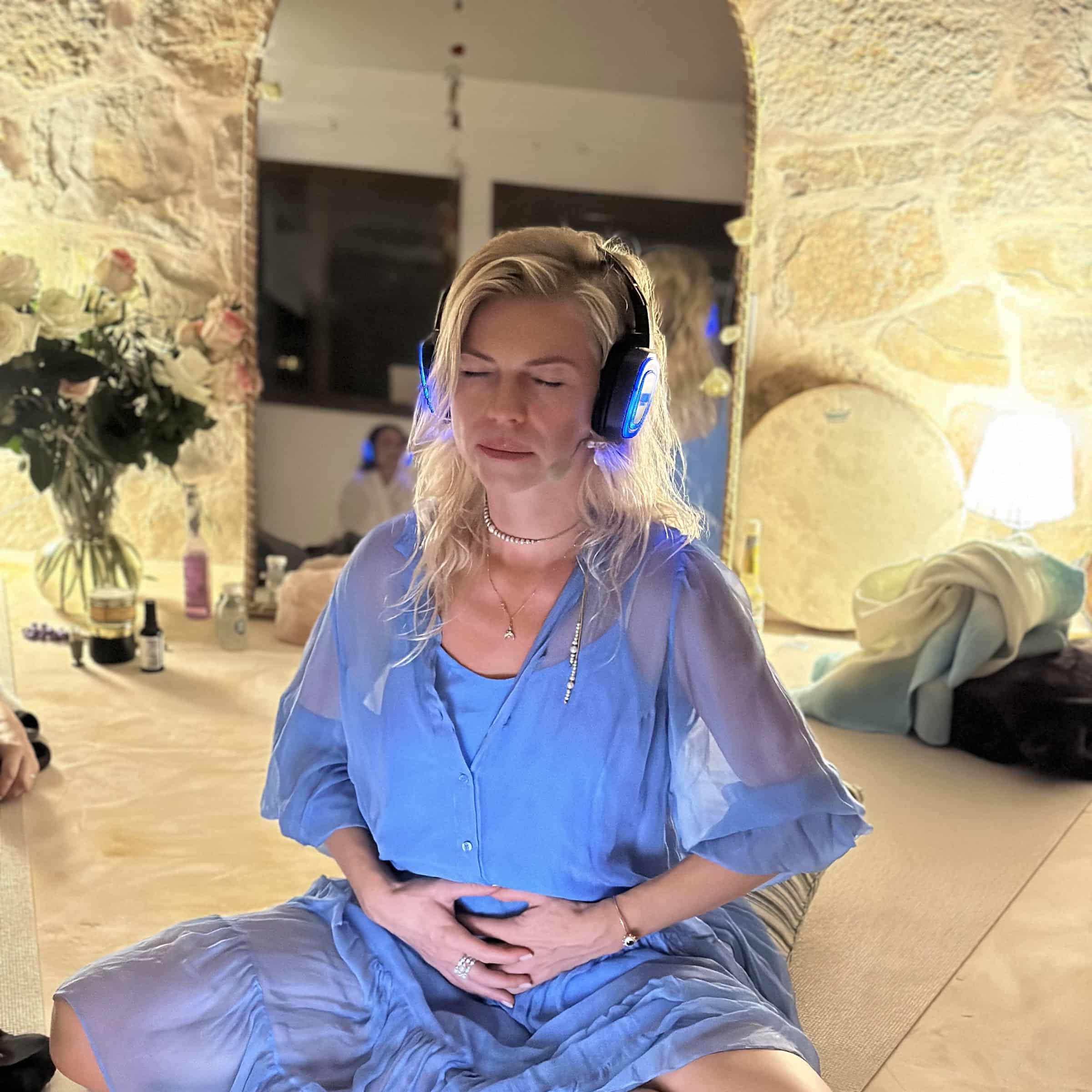 Woman practising breathwork indoors while wearing illuminated SOMA Breath headphones