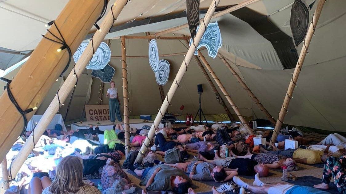 Participants lying on mats beneath a large tent during a guided group breathwork session