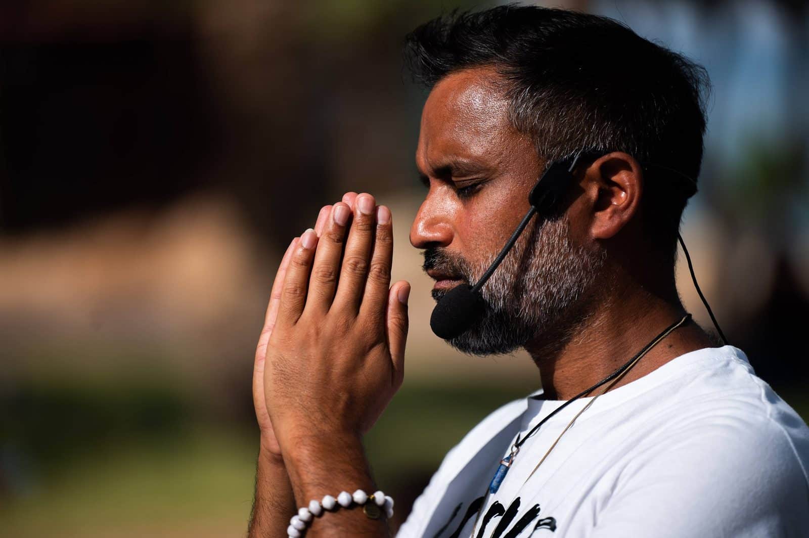 Niraj Naik wearing a headset with his eyes closed and palms together
